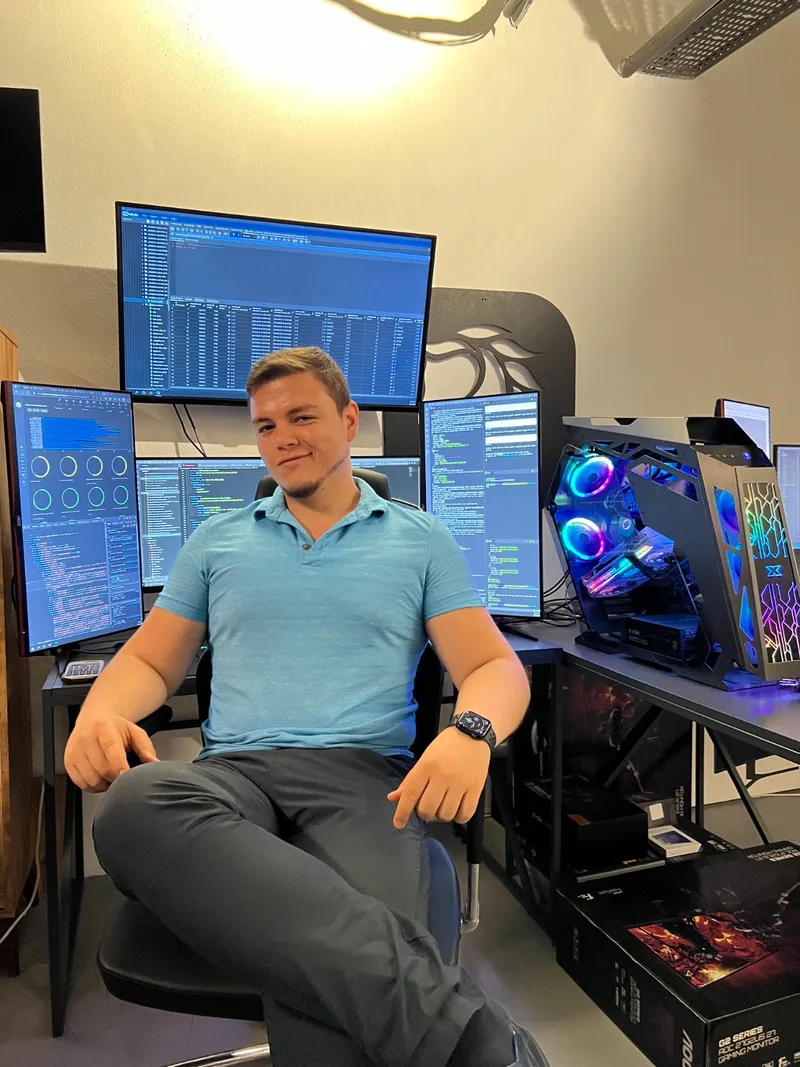 Halis at his workstation, surrounded by monitors and computer hardware.